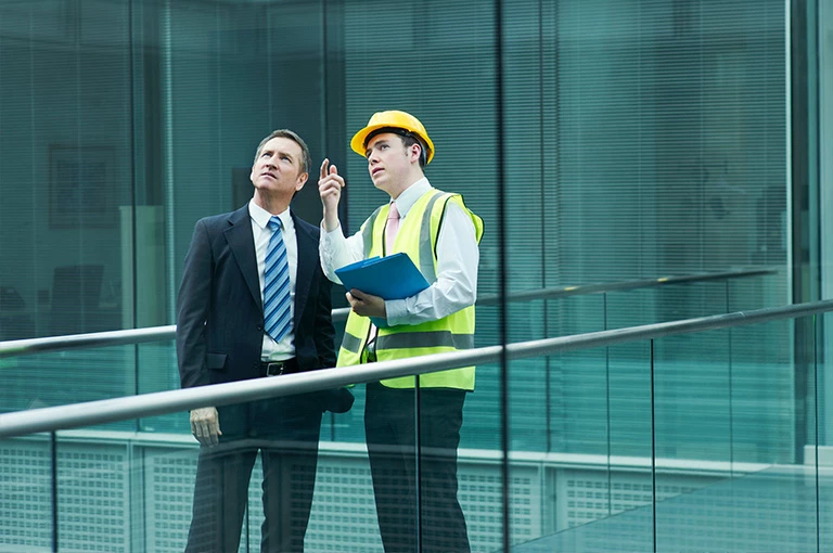Elegancko ubrany mężczyzna rozmawiający z pracownikiem budowy